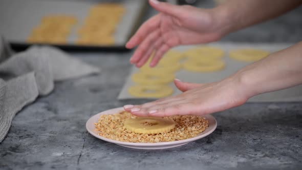 Woman Makes Round Peanut Cookies Sprinkled with Chopped Peanuts