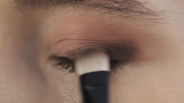 Professional Makeup Artist Is Applying Black Eye Shadows To Upper Eyelid of Model