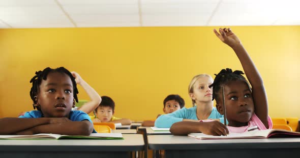 School kids raising hand in classroom alt