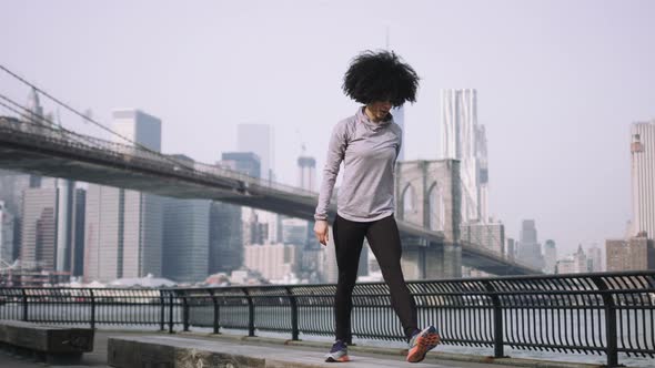 Female fitness model training outside in New York City with skyline and Brooklyn Bridge 