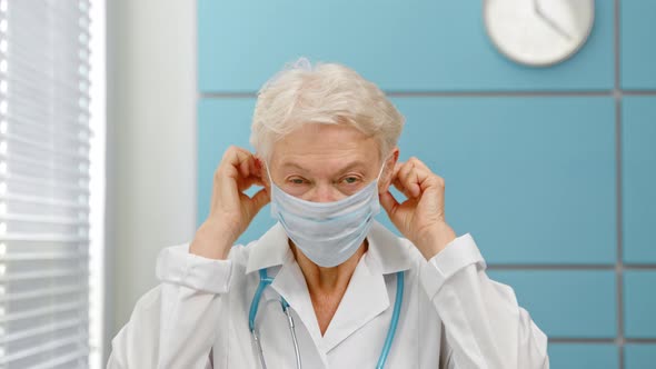 Grey haired senior woman doctor wearing surgical mask alt