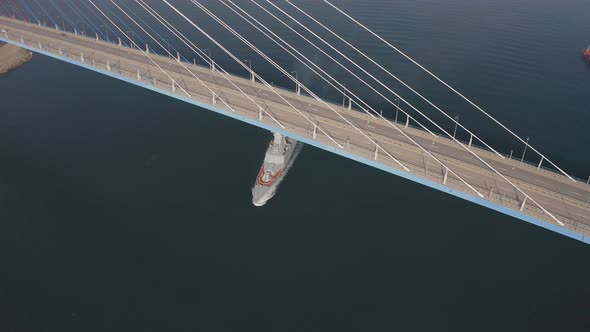 Drone View of a Modern Corvetteclass Ship Going Out to Sea Under the Bridge alt