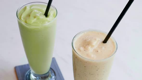 Vegetarian Healthy Smoothies of Raw Avocado and Banana in Glass with Straws alt
