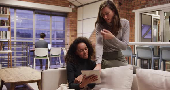 Two creative bussinesswoman discussing over digital table in modern office alt