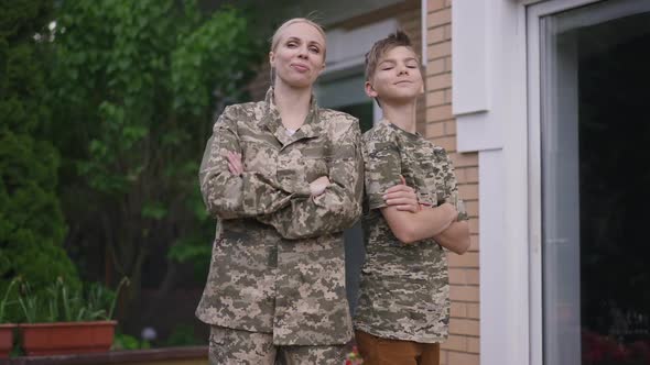 Portrait of Brave Confident Military Mother and Teenage Son in Khaki Camouflage Crossing Hands alt