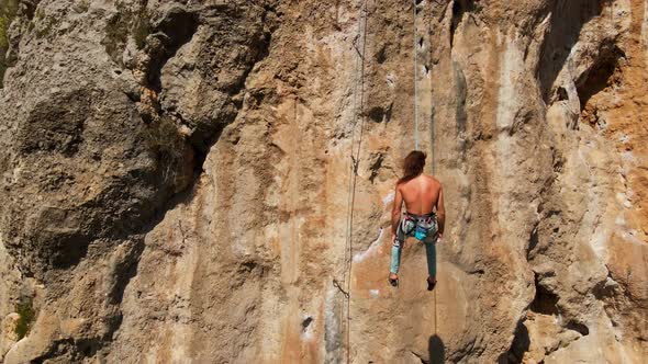 Aerial View From Drone of Strong Athletic Man Rock Climber Descends From High Vertical Cliff on Top alt