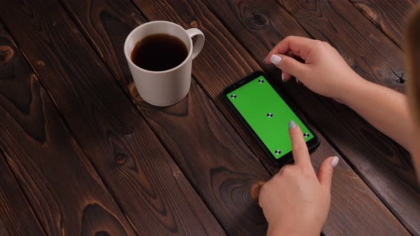Closeup of a Woman Drinking Coffee and Using a Phone with a Green Screen alt
