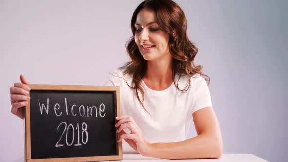 Portrait of smiling woman showing slate with text welcome 2018 4k alt
