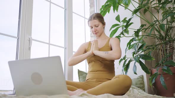 Blonde Woman in Sport Outfit Meditates Watching Tutorial alt