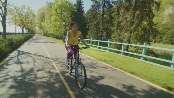 Relaxed Hipster Black Woman Cycling Through Summer Park alt