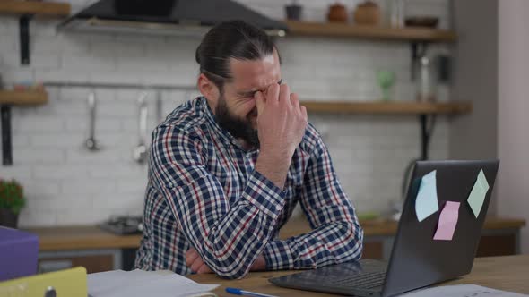 Portrait of Overburdened Bearded Handsome Middle Eastern Man Rubbing Eyes Stretching Neck Typing on alt
