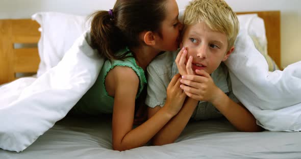 Siblings interacting with each other on bed in bedroom alt