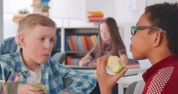 Diverse Schoolkids Sitting at in Classroom Eating Fruits During Break alt