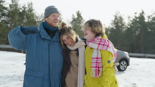 Three young friends chatting with each other while walking in snow during the winter alt