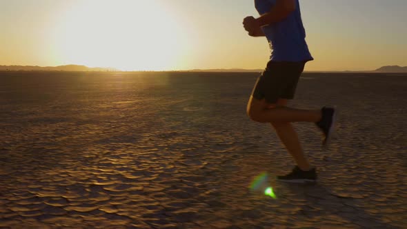 Athletic man working out with battle ropes on a dry lake at sunset alt