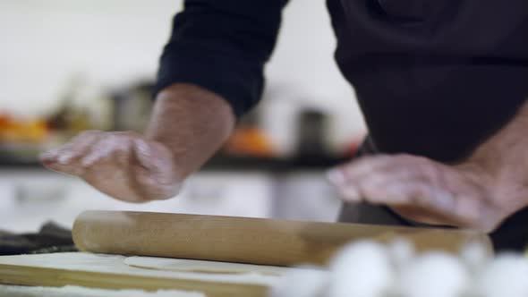 Closeup of Hands Rolls Out the Dough Thinly with a Rolling Pin