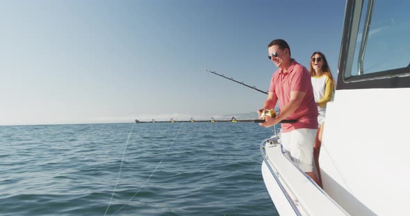 Side view of a Caucasian man and his teenage daughter fishing on boat alt