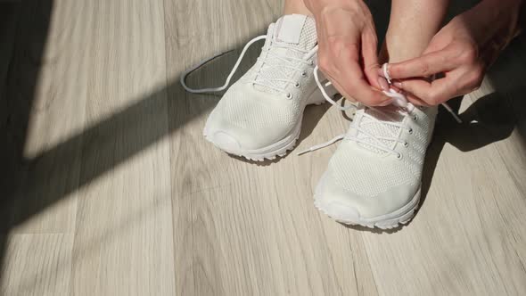 Young Girl Tying Her Shoelaces on Sporty White Sneakers for a Walk or Jogging Outdoors Closeup alt
