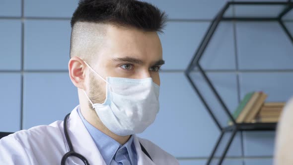 Close up portrait of a Young Male Doctor in a Mask in a Hospital Office alt