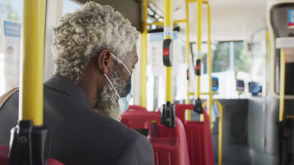 African american senior man wearing face mask travelling in the bus alt