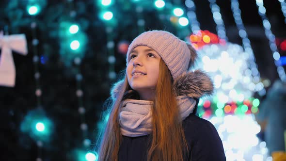 Smiling Teen Girl Looking Up at Christmas Lights alt