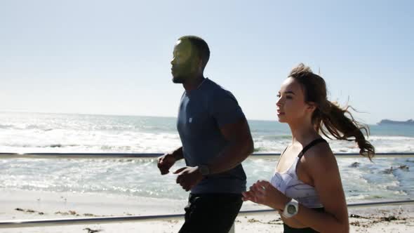 Fit couple jogging on a promenade at beach 4k