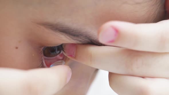 Closeup a Little Girl to Put on Contact Lenses with Fingers and Blinks alt