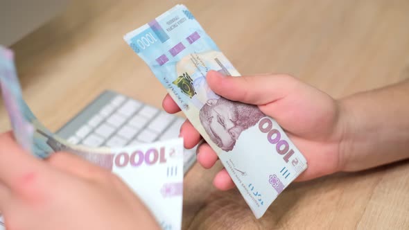 Hands of Unrecognizable Caucasian Man Holds and Counting Ukrainian Hryvnias alt