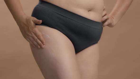 Full Figure Caucasian Woman in Underwear Put Cream on Her Leg and Massage alt