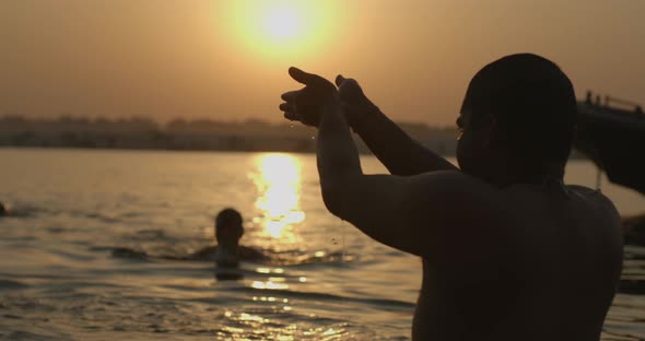 Hindu man praying at sunrise in Ganga river in Varanasi, India alt