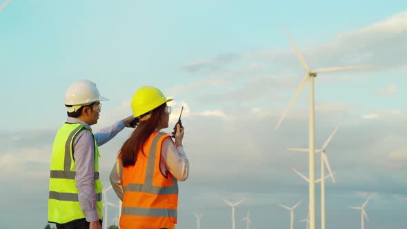 young engineer team using walkie talkie to checking system against wind turbine farm