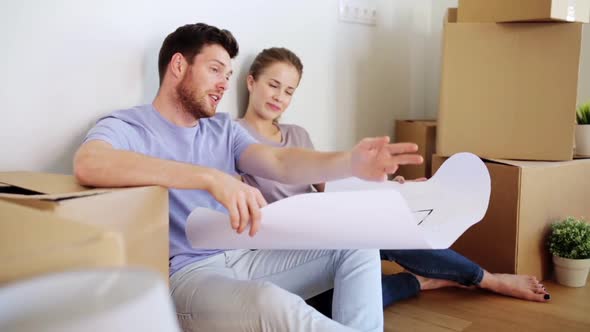 Happy Couple with Blueprint at New Home  alt