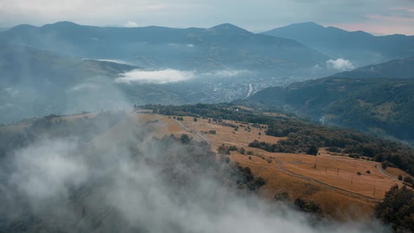 Drone Flying Through Morning Fog Mountain Range in Background