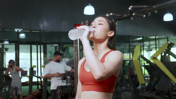 sportswoman drinking water for a refresh during exercise in a sports club. healthy lifestyle concept