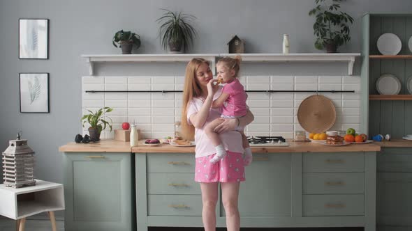 Beautiful Mother Cooking Dinner on Kitchen with Little Kid.