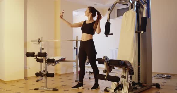 Wide Shot of Slim Confident Sportswoman Taking Selfie in Gym Indoors alt