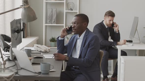 Traders Talking with Investors on Cellphones in Office alt