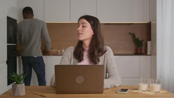 Young Mixed Race Couple Discuss Work on Their Kitchen in a Bright Modern Apartment with a Laptop and alt