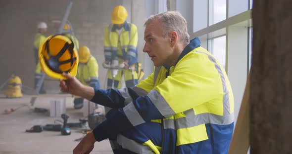 Mature Builder Relaxing at Construction Site During Break alt
