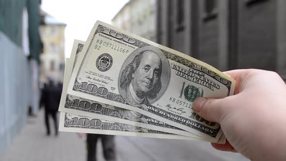 Three Hundred Dollar Bills on Blurred Background of European Old Ancient Street alt