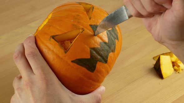 A man carves out a festive Halloween decor with his own hands. Scary pumpkin for Halloween alt