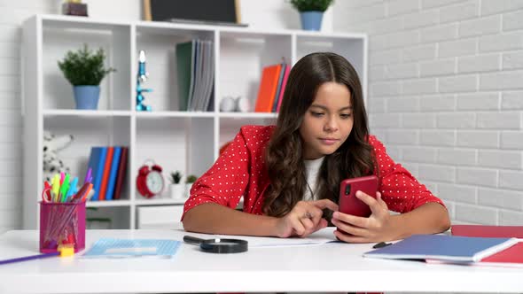 Serious Girl Child Doing Homework Using Mobile Phone at School Desk Smartphone Learning