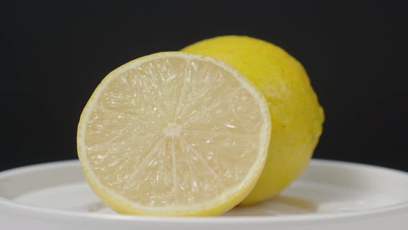 Delicious lemon moving on turntable. Tasty lemons isolate on the black background. Whole and half ye