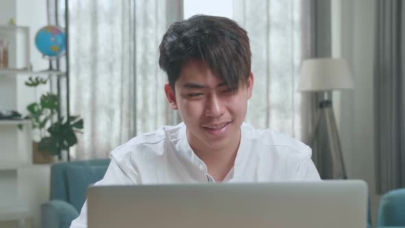Close Up Of A Happy Asian Man Student Using Computer To Study Online At Home alt