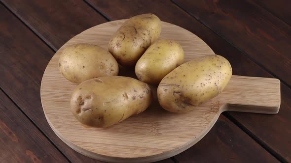 golden yukon potatoes rotating on a wooden table with cutting board