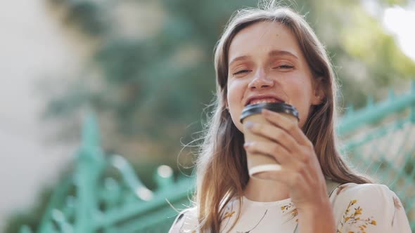 Portrait of Charming Young Happy Caucasian Girl with Brown Hair Blue Eyes and Freckles Holding Coffe alt