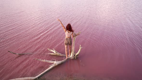 Happy Woman Traveler Raises Hand Up Standing on Background Beautiful Pink Lake alt