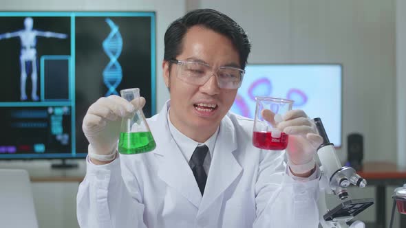 Young Asian Male Research Scientist Holding Glass Test Tube And Speaking To The Camera alt