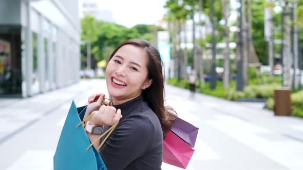 Smiling young Asian woman with shopping colour bags alt