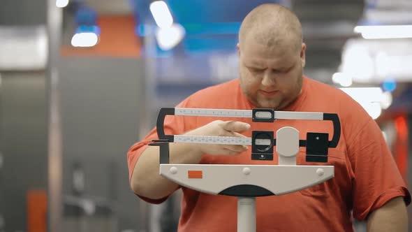 Fat Man Weighing on Medical Scales in Gym. Checking Weight Loss After Workout